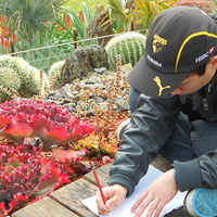 Man wearing Hawthorn hat taking notes with cacti and plants in background