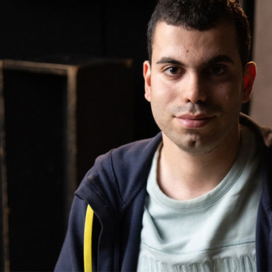 A man wearing a blue and grey hoodie staring directly at the camera.