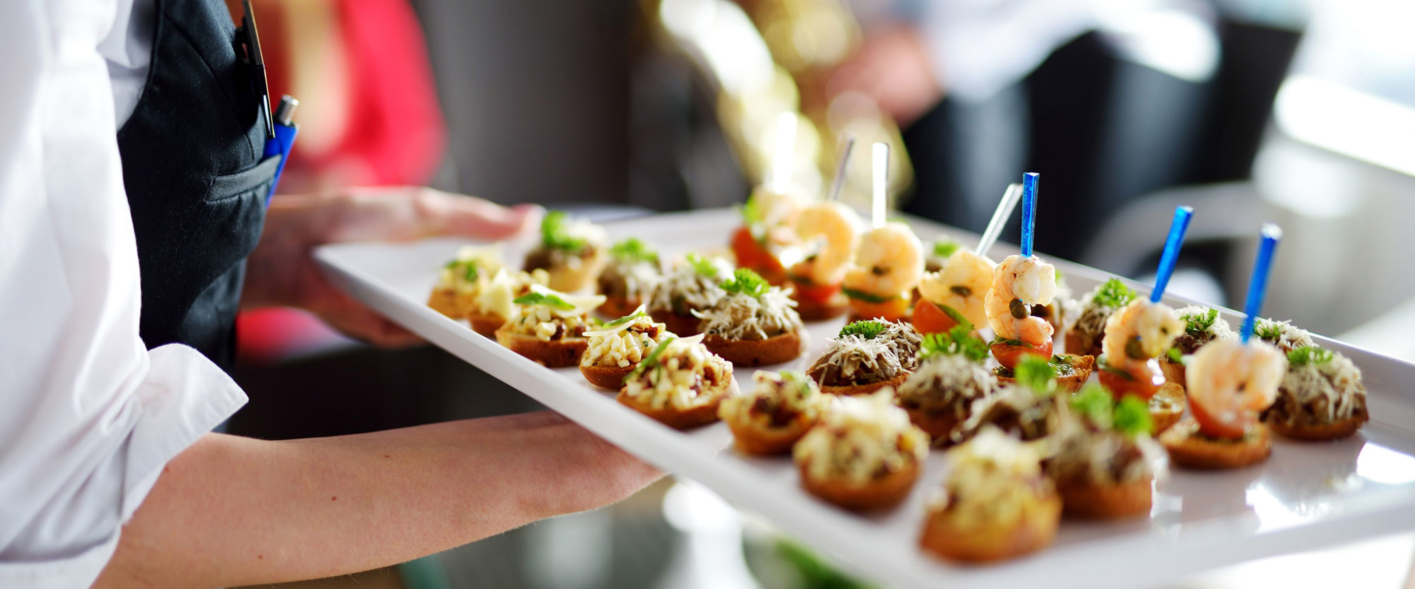 A person holding a tray of nicely prepared foods