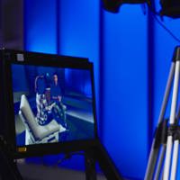 A woman looking into a tv monitor with a camera operator in the background