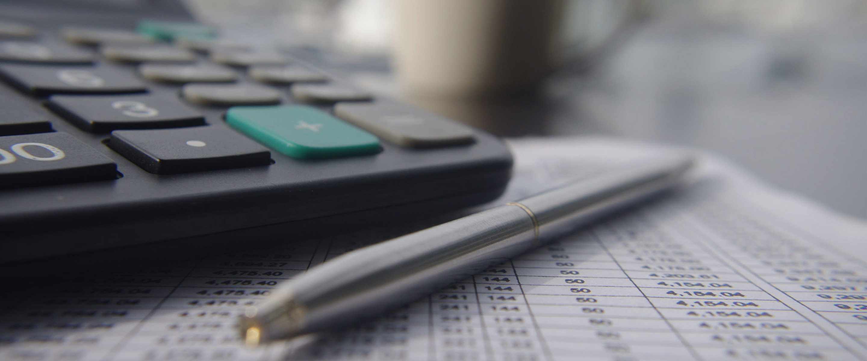 A pen and calculator on a desk, sitting on top of written calculations