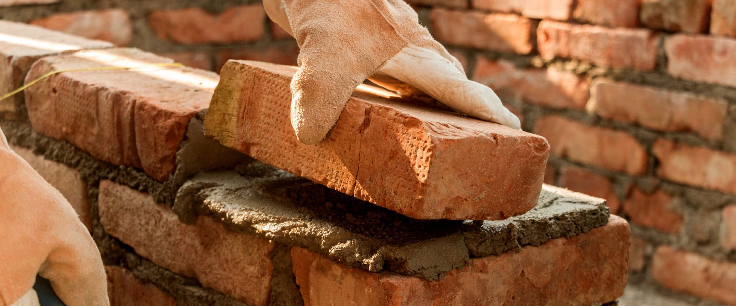 A person laying a brick on top of some mortar 