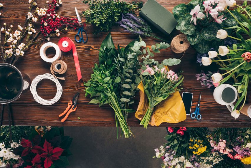 A bird's-eye view of flowers being trimmed and tied together for a bouquet 