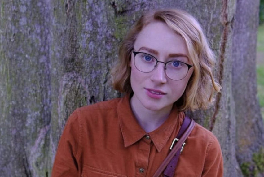 Student Amanda leaning against a tree