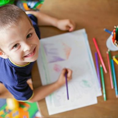 Child looking up at camera while drawing