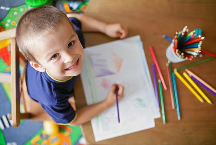 Child looking up at camera while drawing