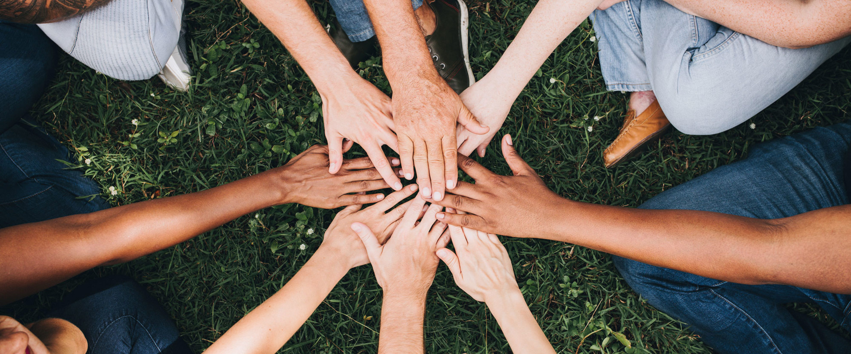 Different people putting their hands in a circle