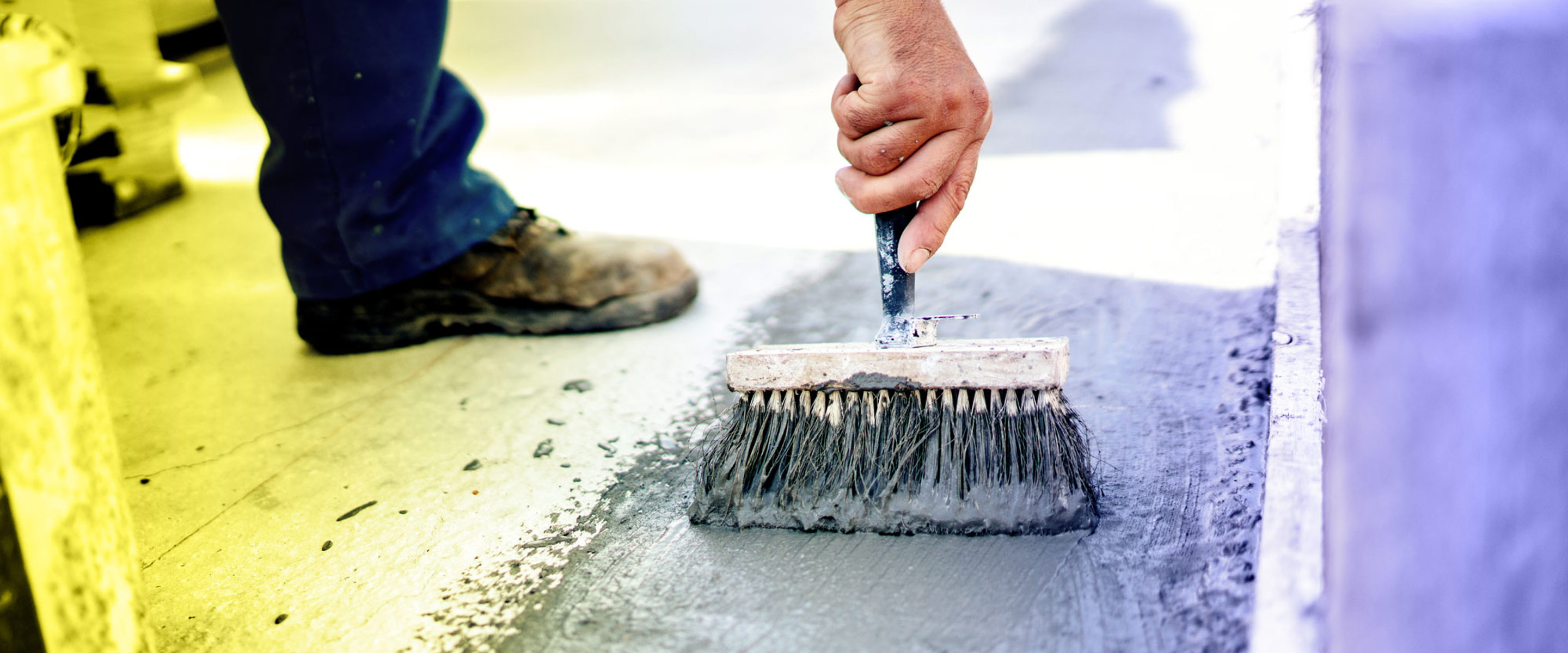 A person using a brush to waterproof the floor of a factory