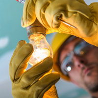 A worm's- eye view of a man holding a switched on light bulb