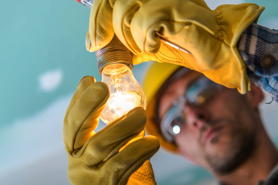 A worm's- eye view of a man holding a switched on light bulb