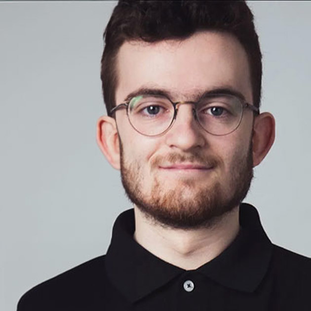 A man wearing glasses and a black shirt smiles to the camera