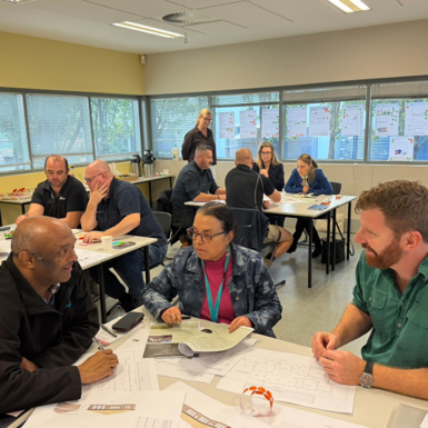 Workshop participants sit at desks with educators and industry representatives.