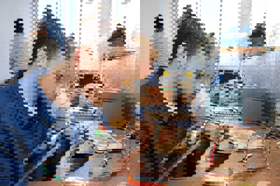 Student using a  jeweller's tool at a workshop station