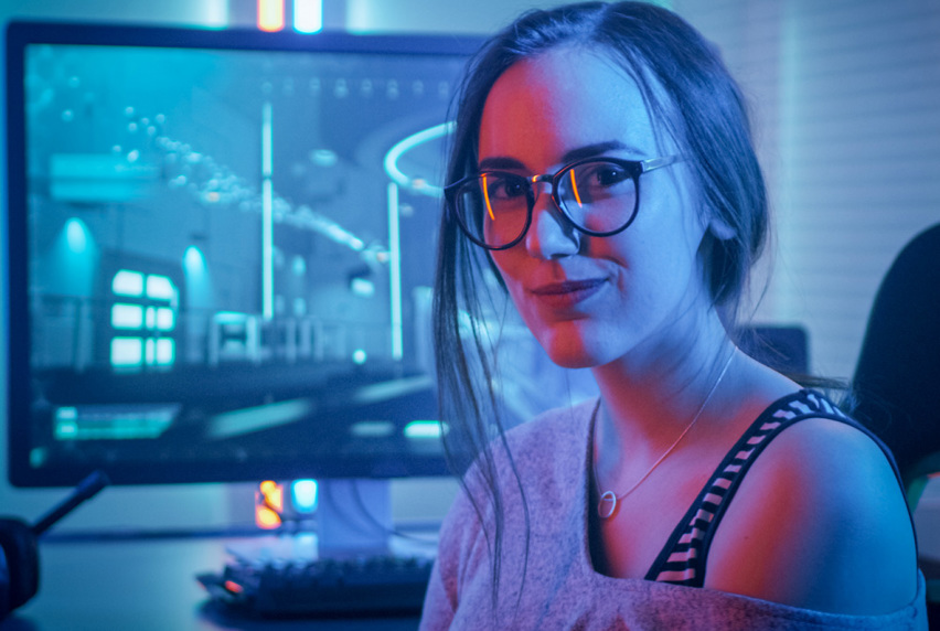 Information technology student posing for photo, with screen monitor behind her.