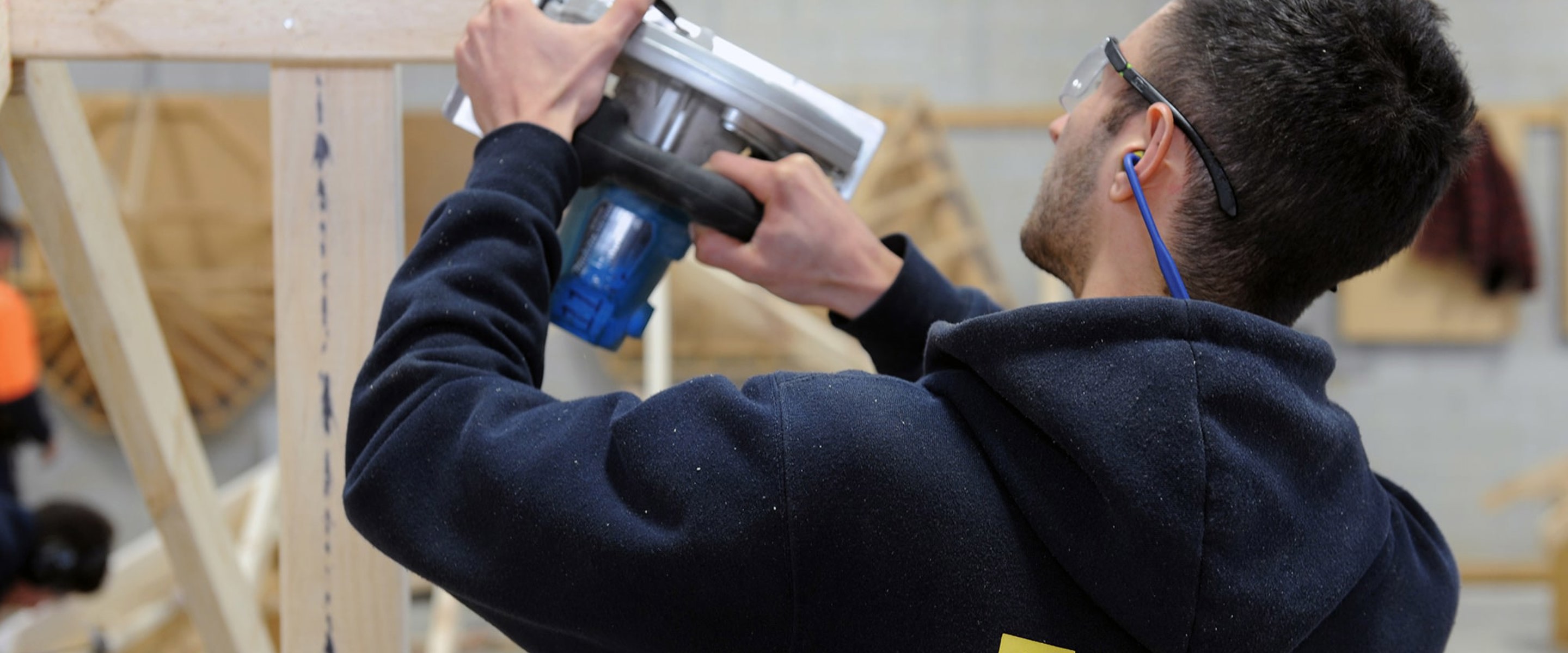 Building Surveying and Construction student with using a hand saw on a timber frame