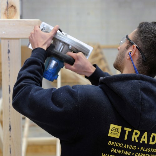 Building Surveying and Construction student with using a hand saw on a timber frame