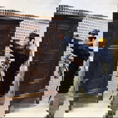 Carpentry student with compressed air lacquer gun and small free standing cabinet