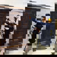 Carpentry student with compressed air lacquer gun and small free standing cabinet