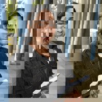 Community Services student leaning against a pole outside a building on Melbourne Polytechnic campus