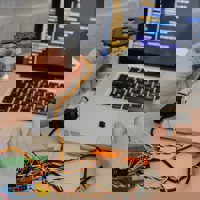 Electronics and Electrical student testing electonic project device with software on laptop