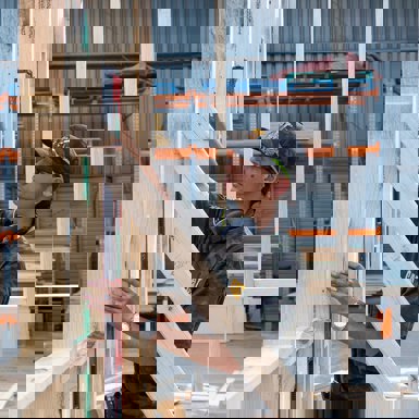 Carpentry student checking level of wooden frame work