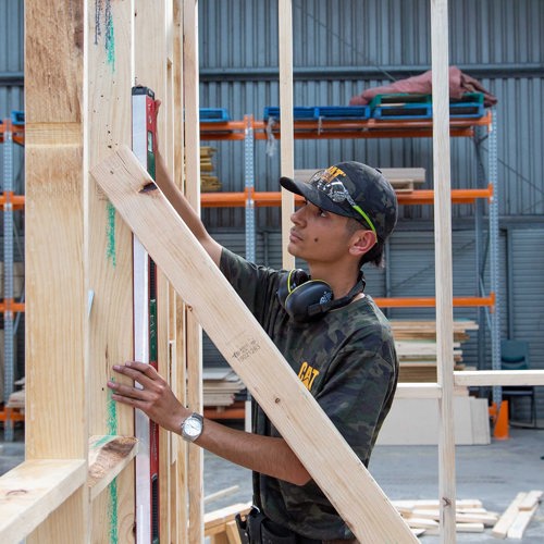 Carpentry student checking level of wooden frame work