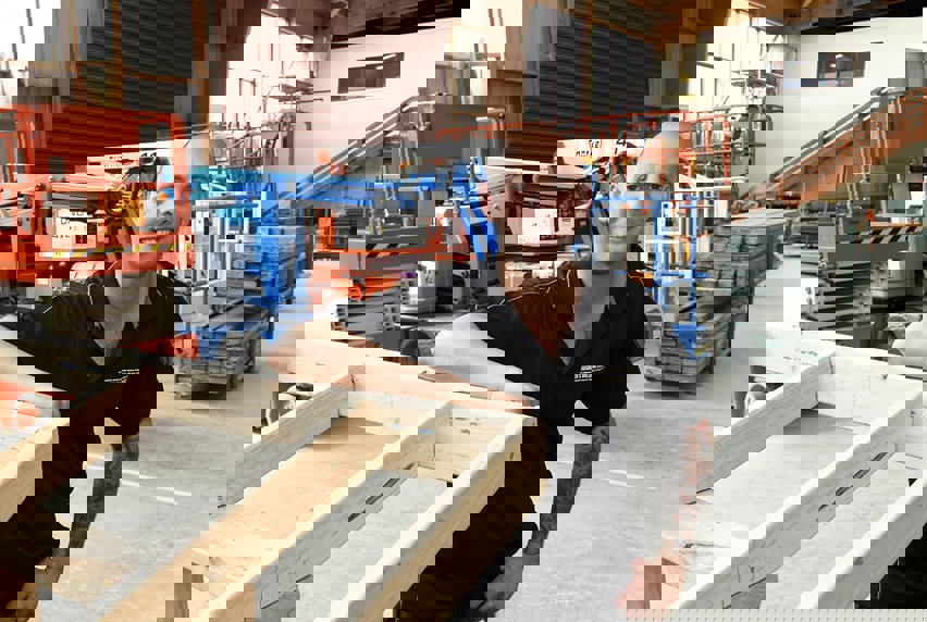 Andrew Guglielmino leaning on a wooden frame in purpose built practical industry enviornment shed on campus