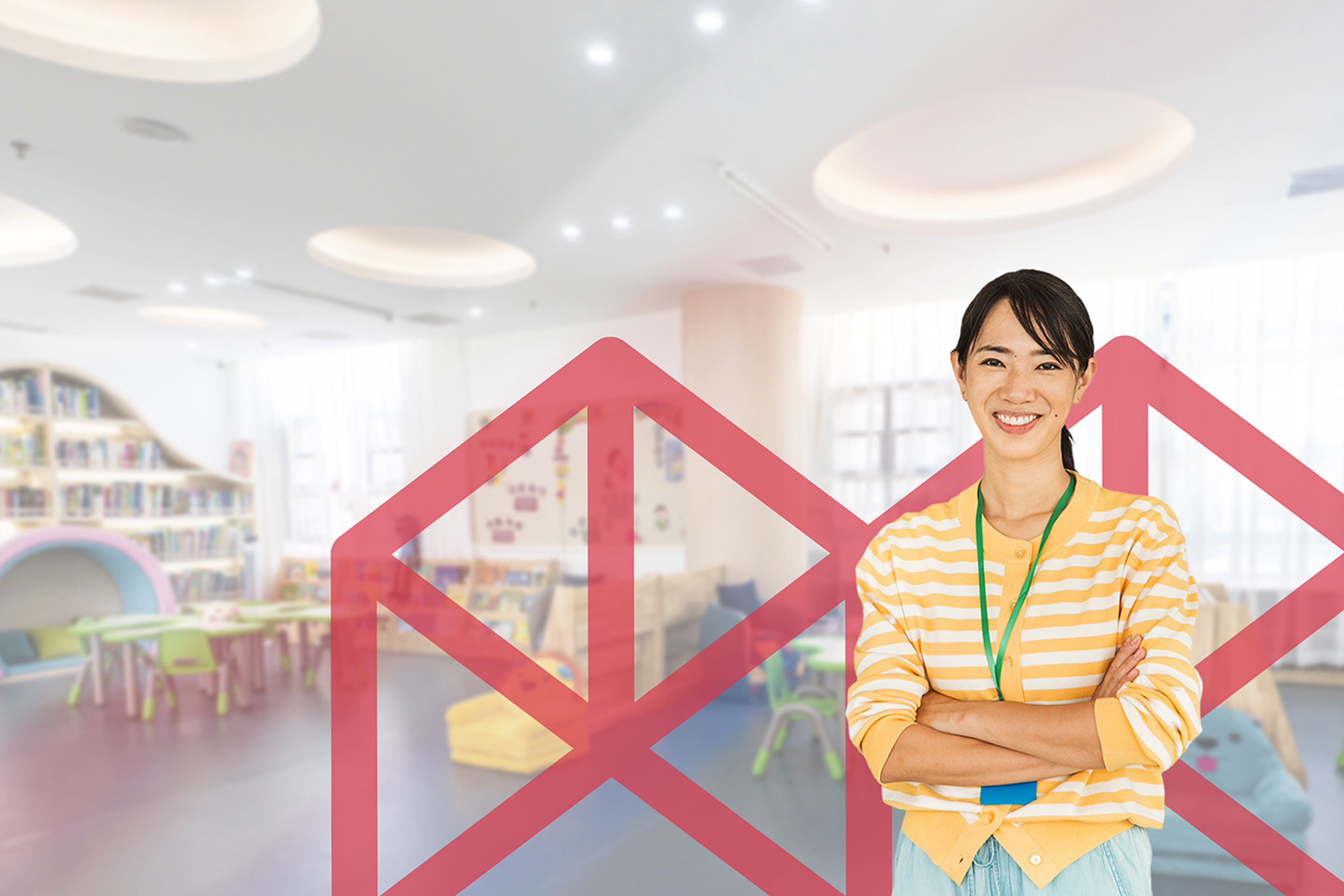 Woman in a colourful early childhood classroom, wearing bright clothes and smiling warmly.