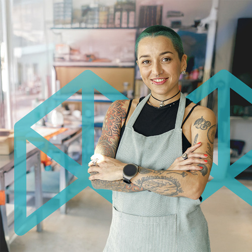 Person standing standing confidently in an art studio with a large light blue Melbourne Polytechnic logo in the background.
