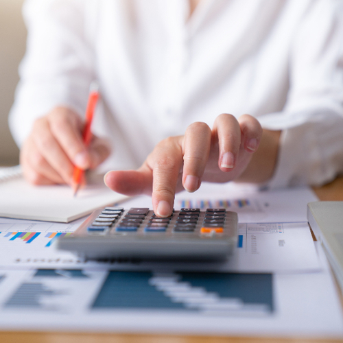 A photo of a person using a calculator and laptop.