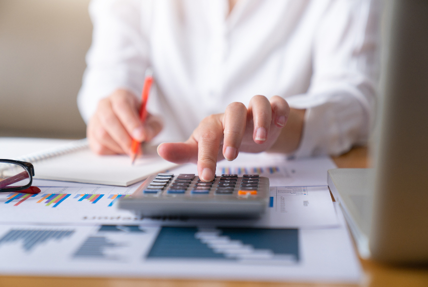 A photo of a person using a calculator and laptop.
