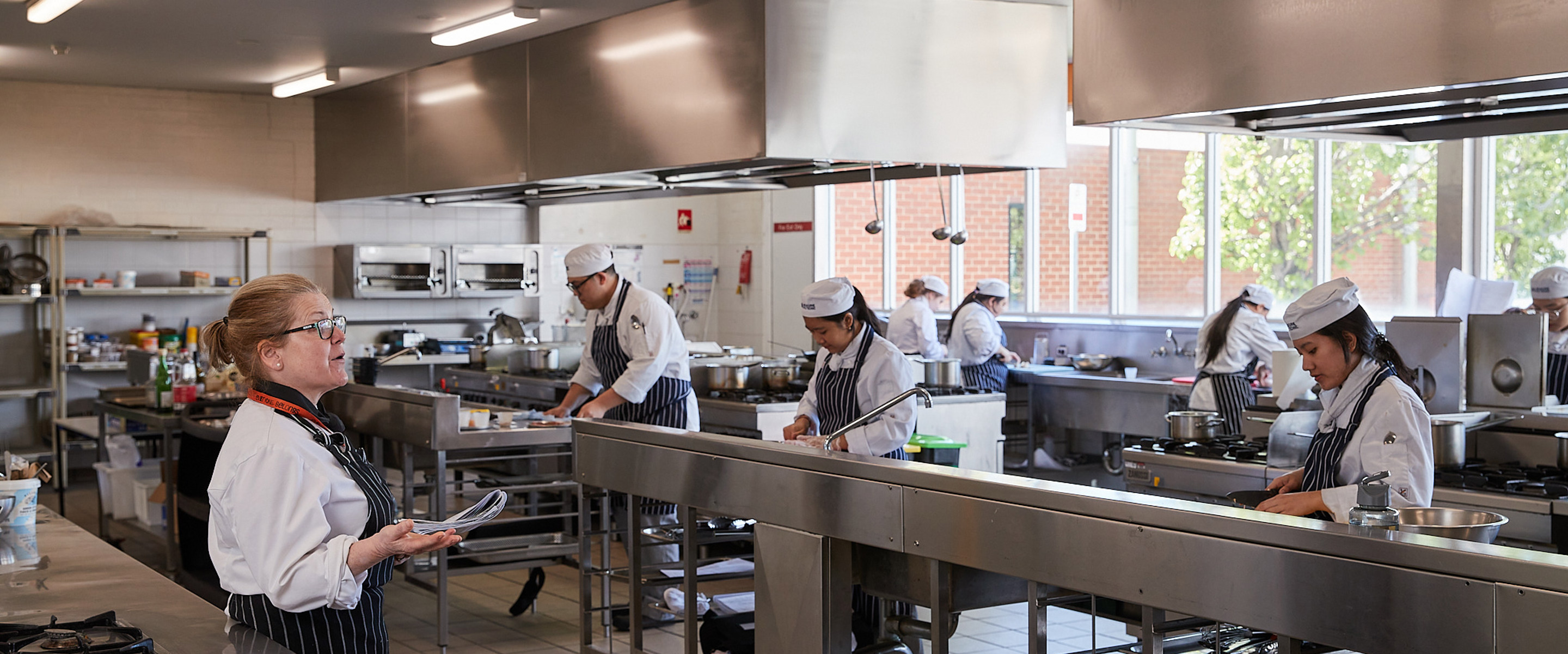 Preston hospitality cookery students preparing food in kitchen facility while under instruction.