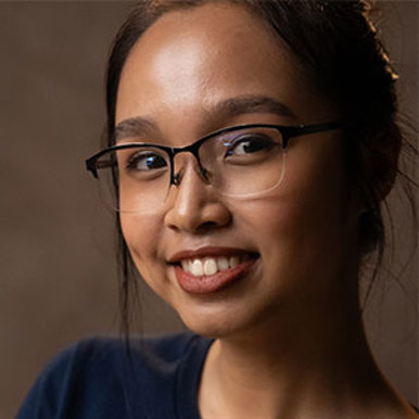 A woman wearing glasses and a blue shirt, posing for the camera