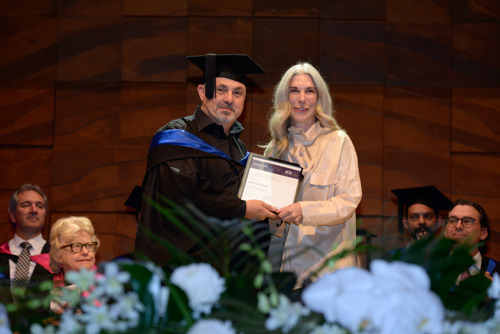 Beth Gregory posing with testamur at graduation ceremony