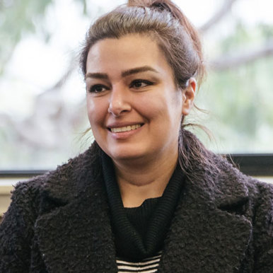 Portrait of a female wearing a charcoal coloured knit jacket, sitting in front of a window