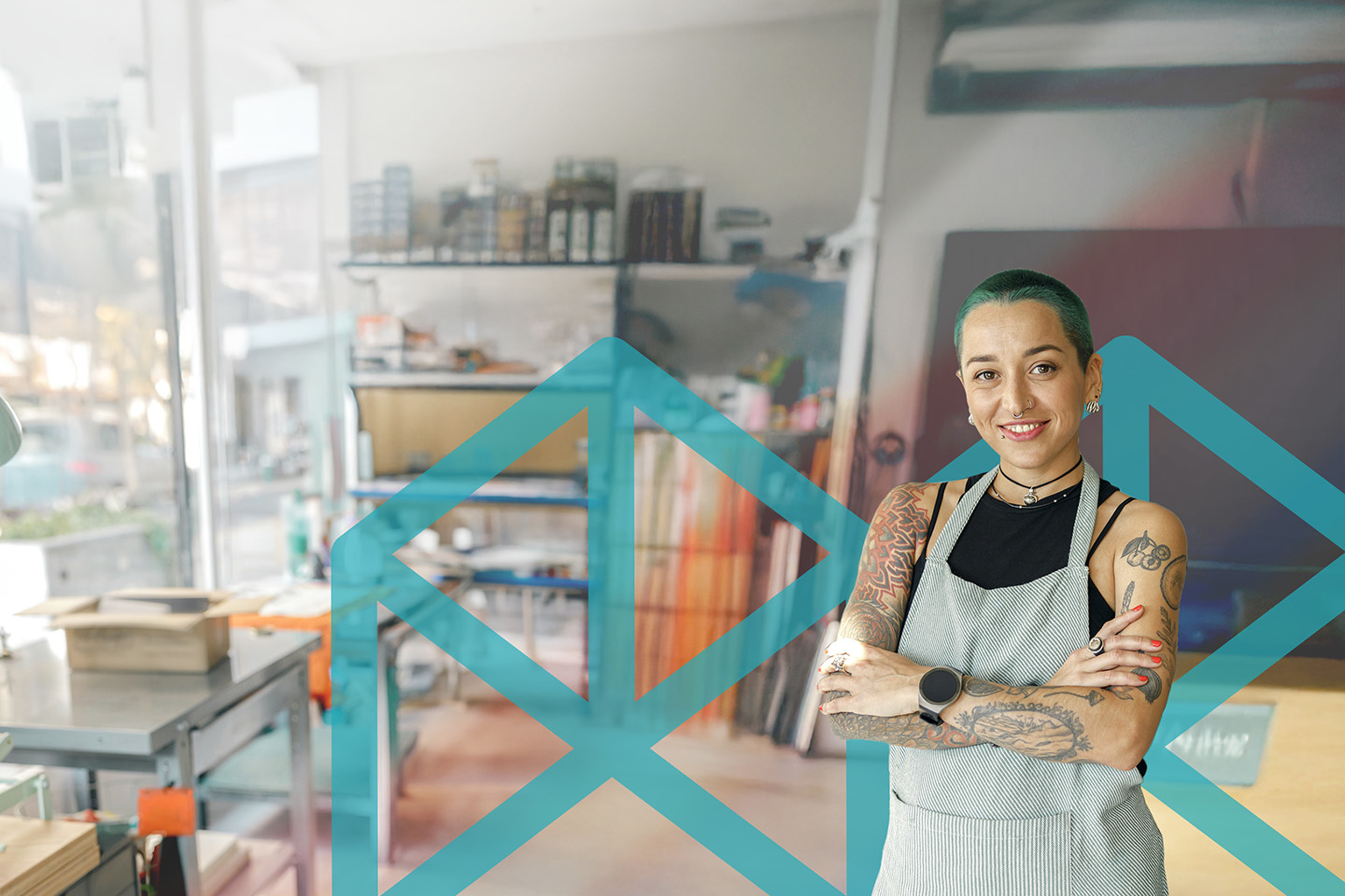 Person standing standing confidently in an art studio with a large light blue Melbourne Polytechnic logo in the background.