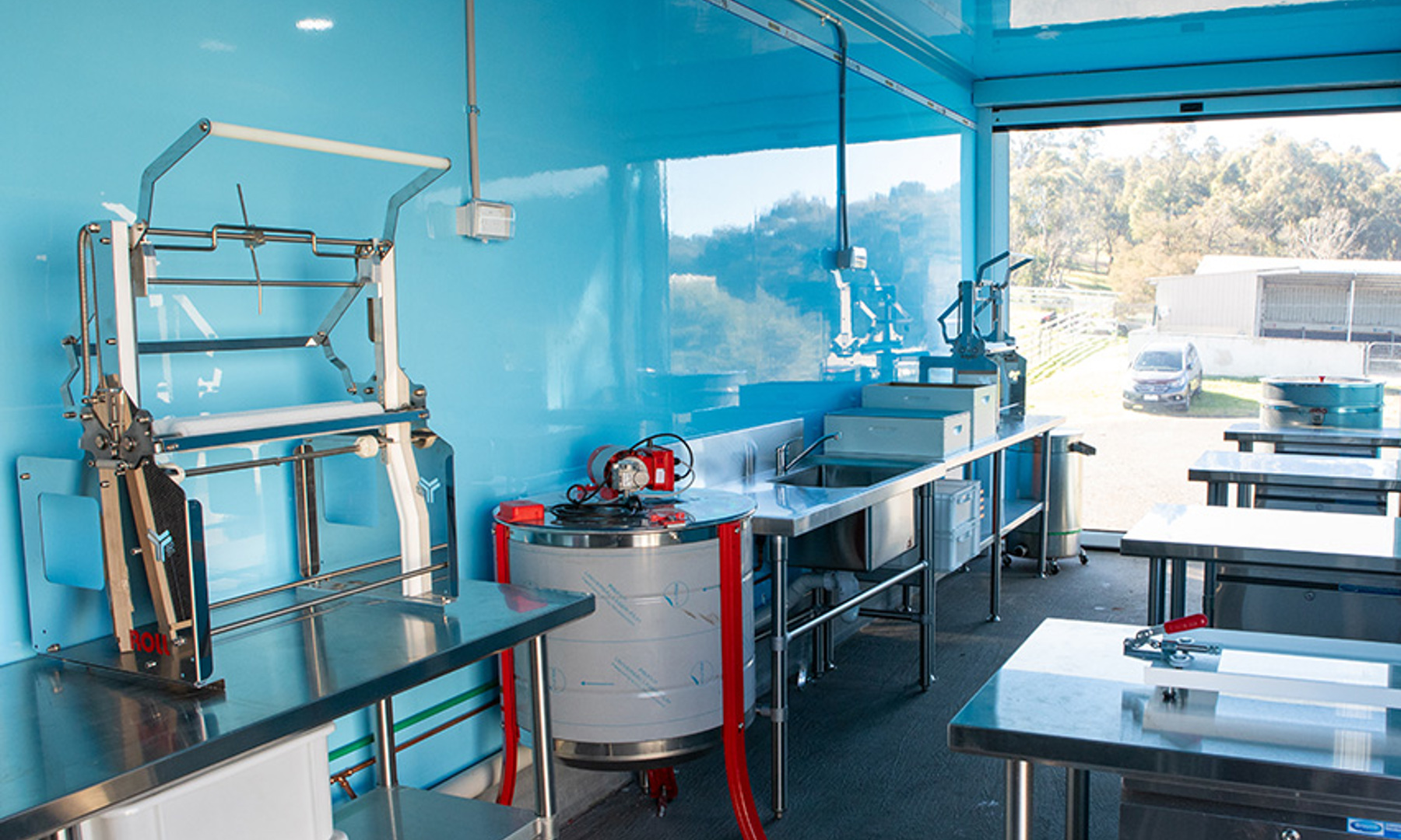 Beekeeping workshop equipment set up within a glossy light blue truck interior. 