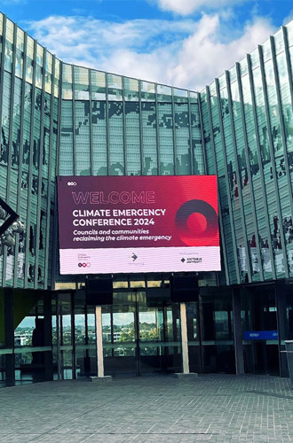 A large digital screen showcasing the conference banner at the entrance of the venue