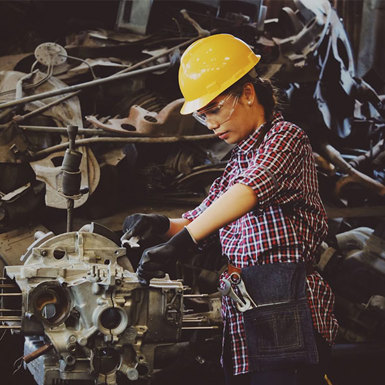 Female Mechanical Engineer wearing safety gear, working on a piece of machinery 