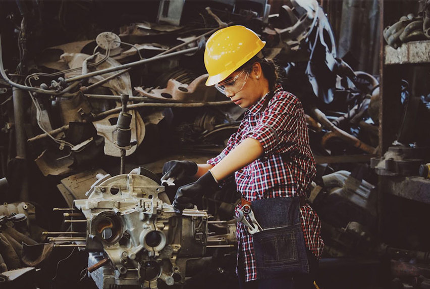 Female Mechanical Engineer wearing safety gear, working on a piece of machinery