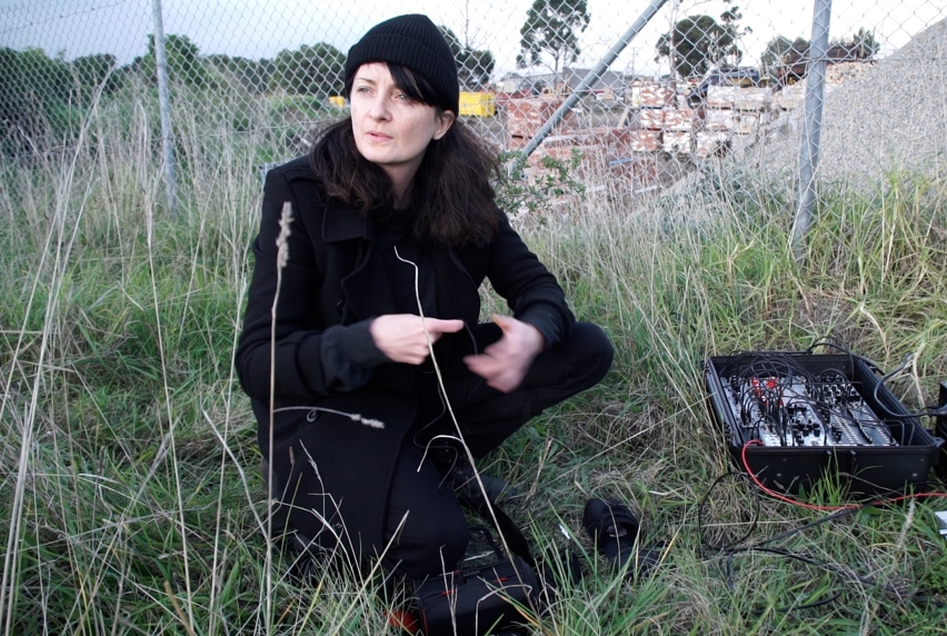 Edwina Stevens, a Lecturer in Music at Melbourne Polytechnic, sampling sounds outdoors with bricks and sand in the background.