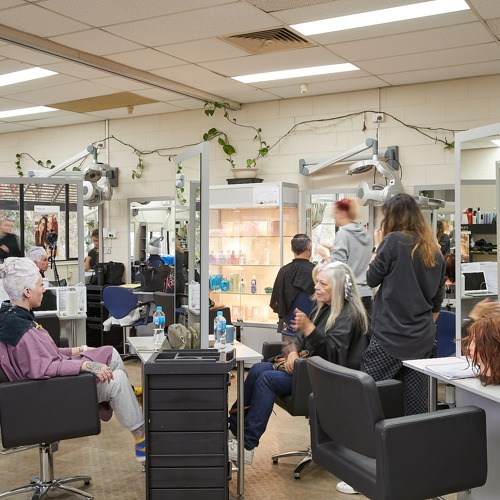 A lively Melbourne Polytechnic hairdressing salon training room with students practicing techniques.