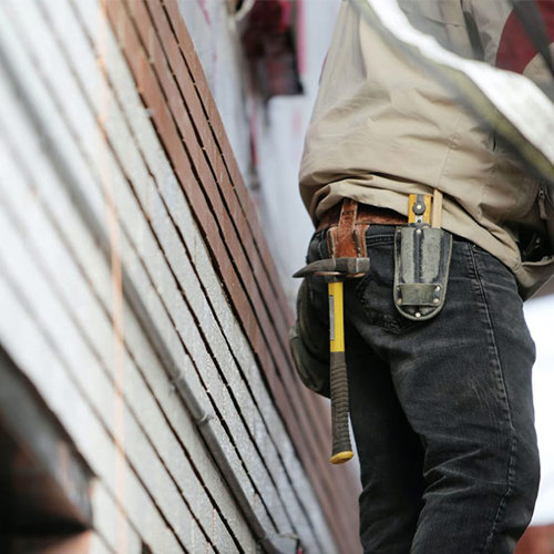 The back of a carpenter showing his tool belt with a hammer and measuring tape 