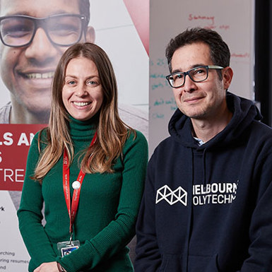 A man and a woman smiling while standing in front of a 'Skills and Jobs Centre' banner.