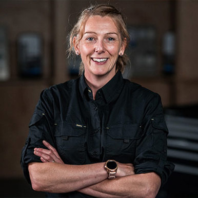 A woman in a black shirt stands confidently, her arms crossed.