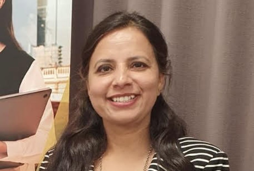 A woman with long hair wearing a black and white striped blazer and smiling warmly at the camera.