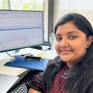 Shan, OQP student, sitting at a desk smiling