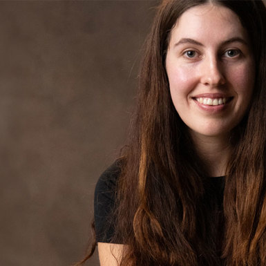 A woman with long brown hair wearing a black shirt smiling