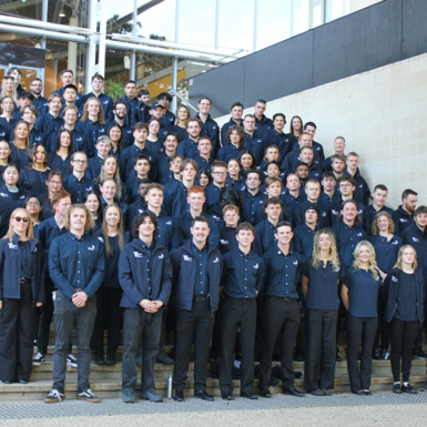 A large group of student competitors on the steps of Brisbane Convention and Exhibition Centre. They are all dressed in a blue WorldSkills uniform with black pants.