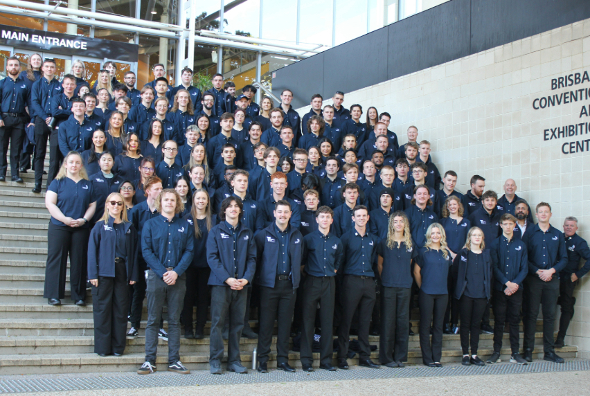 A large group of student competitors on the steps of Brisbane Convention and Exhibition Centre. They are all dressed in a blue WorldSkills uniform with black pants.